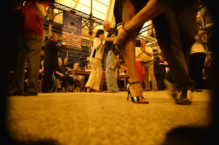 Parejas bailando tango en Joventango. la toma, desde el piso, muestra en primer plano los pies de una bailarina. de fondo, varias parejas bailando