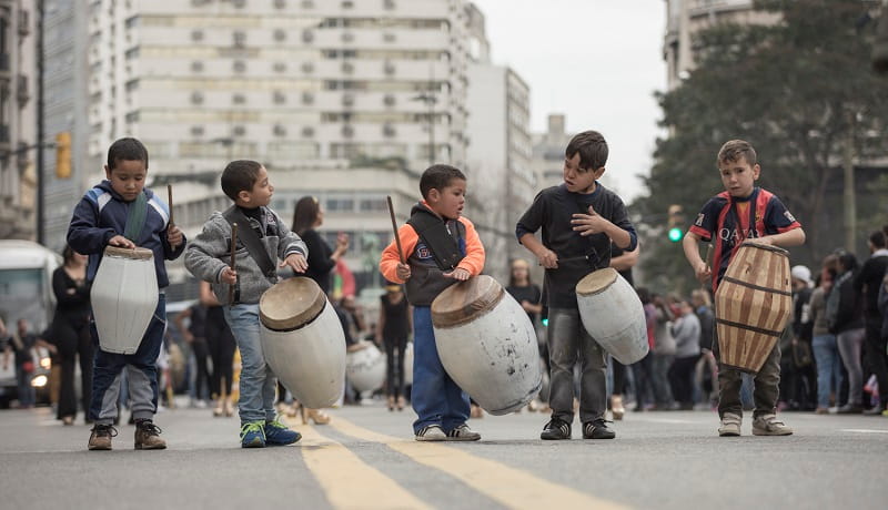 Varios niños tocan candombe con sus tambores por la avenida 18 de julio