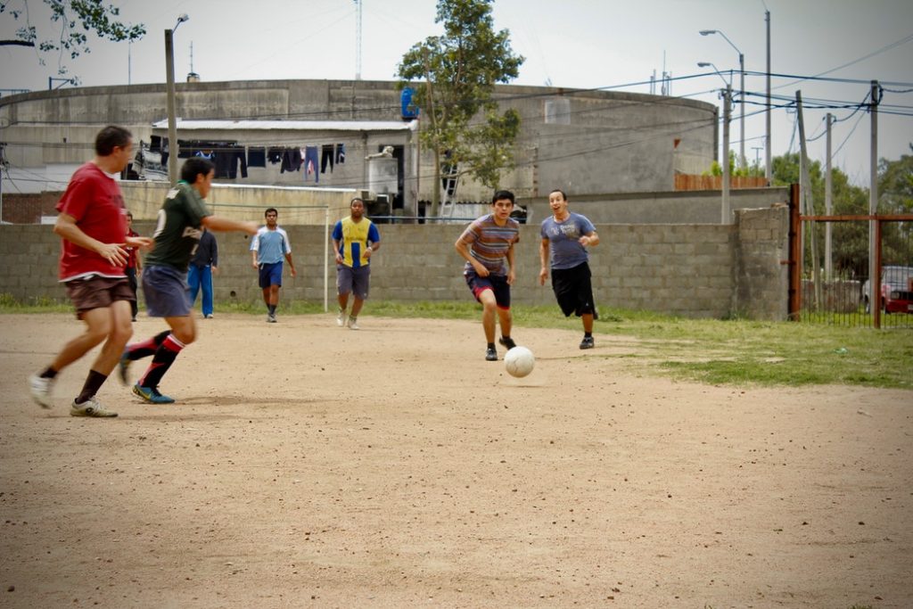 jóvenes jugando al fútbol en una cancha de barrio sin césped tradiciones uruguayas