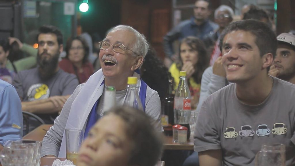 hinchas mirando sonrientes un partido de uruguay en un bar fútbol uruguayo