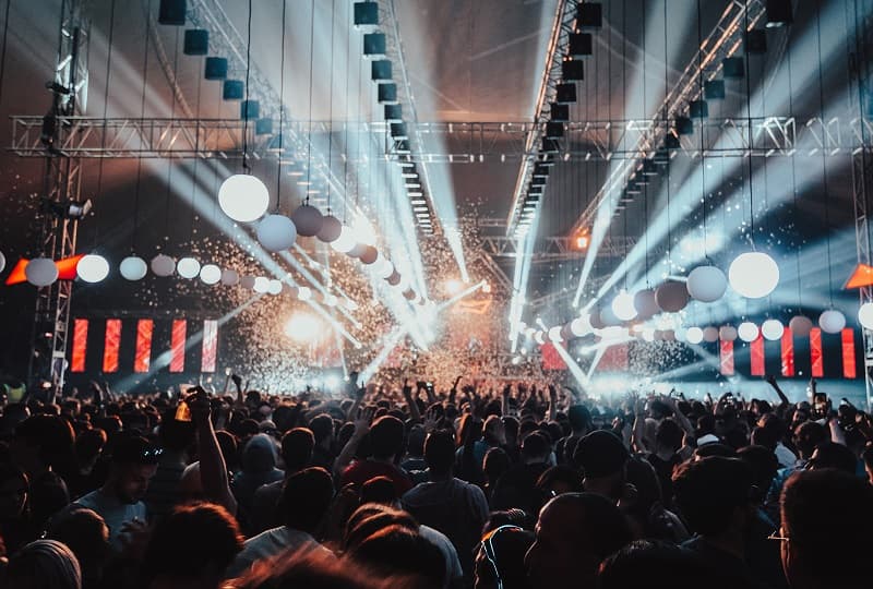Imagen de la fiesta Coccon; cientos de personas bailando frente a un escenario desde el que salen luces y humo