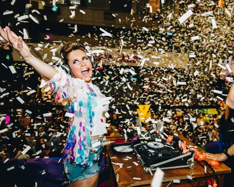 Imagen de Paola Dalto detrás de una bandeja de discos bajo una lluvia de papelitos de dolores