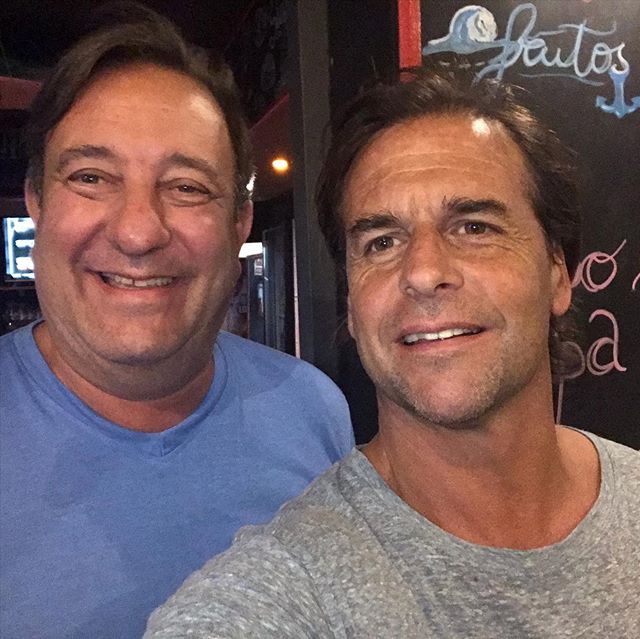 Imagen en primer plano de Luis Lacalle Pou junto al periodista Sergio Herrera, sonrientes, de frente a la cámara, dentro de un restaurante