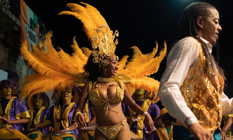 Imagen de una vedette bailando al frente de varias personas que tocan tambores