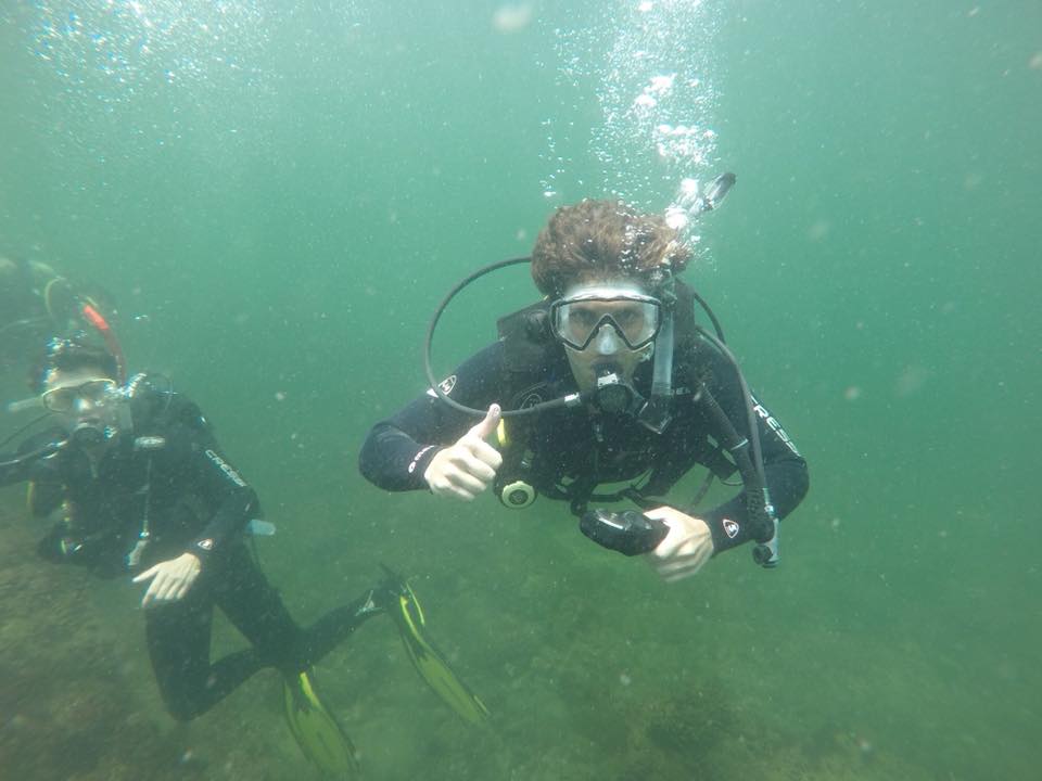 Imagen de dos personas buceando bajo el océano; uno de ellos levanta el pulgar a la cámara