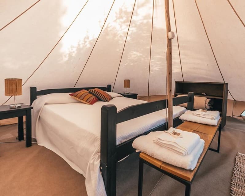 Vista interior de una tienda, dentro de la cual hay una cama de dos plazas