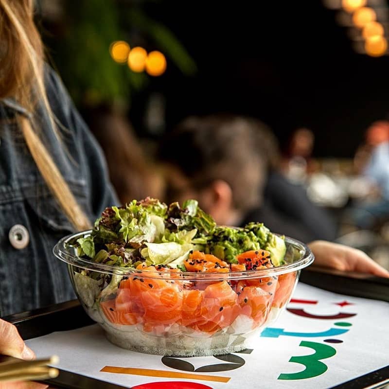 Una mujer sostiene una bandeja sobre la que hay un bowl con ensalada