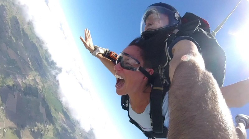 Una mujer grita mientras cae en caída libre en un salto en paracaidas tandem