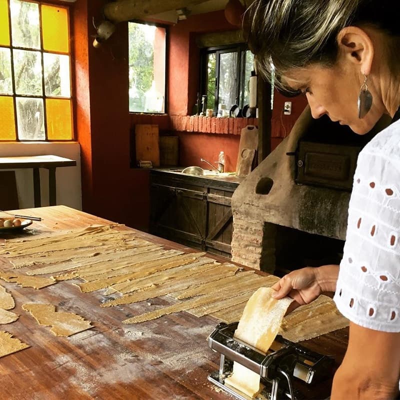 Una mujer elabora pasta artesanal sobre una mesada de madera