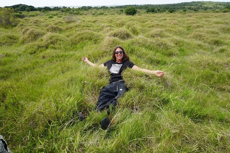 Una mujer, sonriente, acostada sobre un campo verde