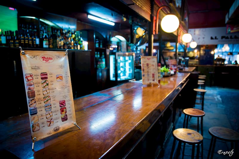 Imegen de una barra del Mercado del Puerto de Montevideo, detrás de la cual hay algunas botellas